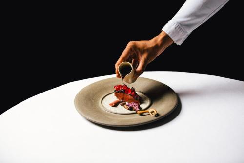 a person is serving food on a plate on a table at The Dylan Amsterdam - The Leading Hotels of the World in Amsterdam