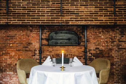 a table with a candle in front of a brick wall at The Dylan Amsterdam - The Leading Hotels of the World in Amsterdam