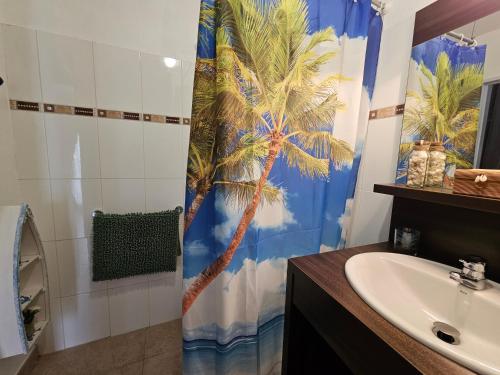 baño con cortina de ducha de palmera y lavamanos en Appartement Disneyland Paris Montevrain, en Montévrain