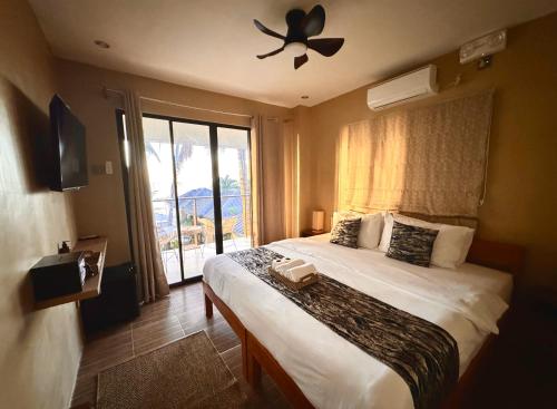 a bedroom with a bed with a ceiling fan and a window at Southseas Beach Resort and Dive Center in Santander