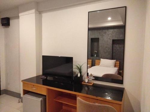 a bedroom with a bed and a desk with a mirror at Pilatus Apartment in Loei