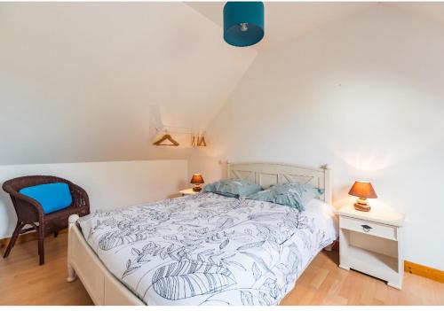a bedroom with a white bed and a chair at La Maison Bleue - 300m de la mer in Pleubian