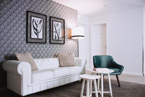 a living room with a white couch and a green chair at Rio Art Hotel in Setúbal
