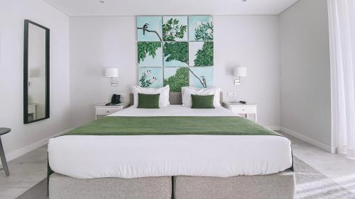 1 dormitorio blanco con 1 cama grande con manta verde en Rio Art Hotel en Setúbal