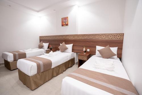 due letti in una camera d'albergo con pareti bianche di فندق سيف بلص 1 من سما العزيزية a La Mecca