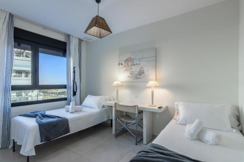 une chambre avec deux lits et un bureau et une fenêtre dans l'établissement Ocean Homes by Ĥ - Playa de los Haraganes HOHH7104P70, à Isla Canela