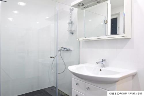 a white bathroom with a sink and a shower at Downtown Belgrade Apartments in Belgrade