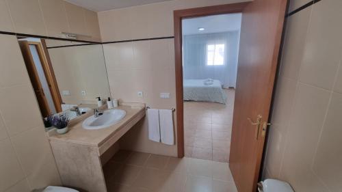 a bathroom with a sink and a toilet and a mirror at Moderno Apartamento 3 dormitorios y piscina in La Algaba