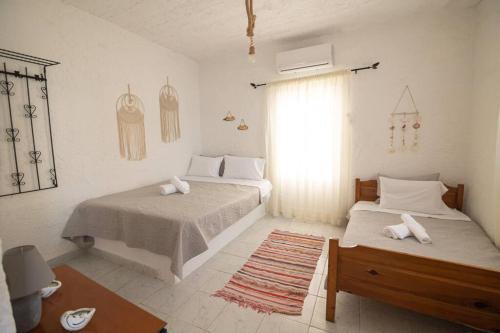 um quarto branco com 2 camas e uma janela em Beachfront Lovely Small House on the Sea em Paránimfoi