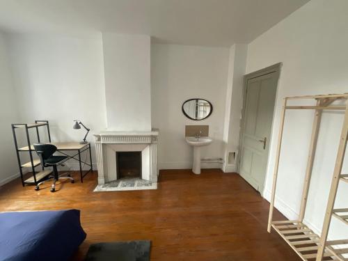 Zimmer mit einem Kamin, einem Tisch und einem Schreibtisch in der Unterkunft Ancienne maison de maitre in Douai