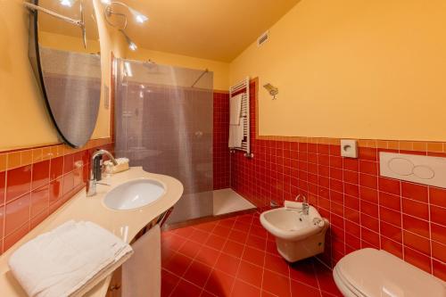 a red tiled bathroom with a sink and a toilet at La Darsena Boutique Hotel & Restaurant in Tremezzo