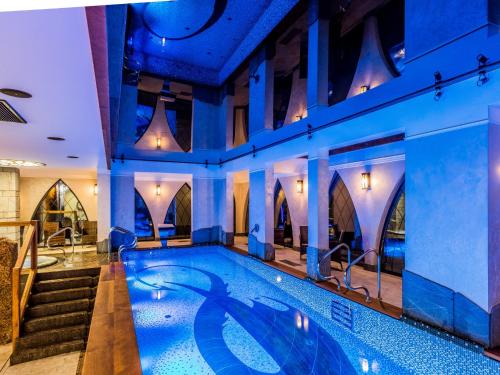 a swimming pool in a hotel with blue lighting at Norweska Dolina Luxury Resort in Szklarska Poręba