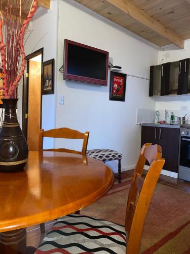 a living room with a wooden table and a kitchen at Cabaña Pelluhue in Pelluhue