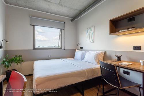 ein Schlafzimmer mit Bett, Schreibtisch und Fenster in der Unterkunft Caza Noz by Viva - Apartamentos com ótima estrutura e área comum próximo à USP e Butantã in São Paulo