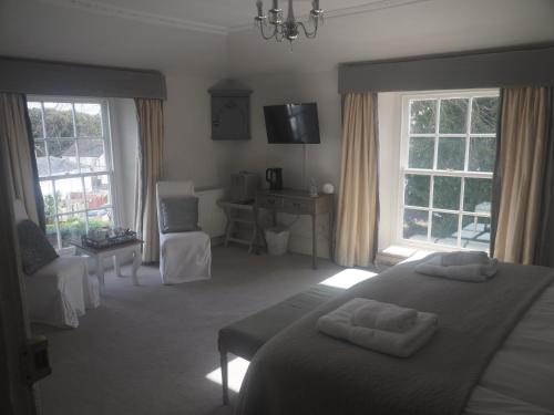a bedroom with a bed and two chairs and windows at The Mount in Bideford