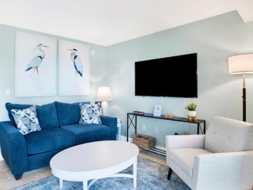 a living room with a blue couch and a tv at Regency Towers #103 East in Pensacola Beach