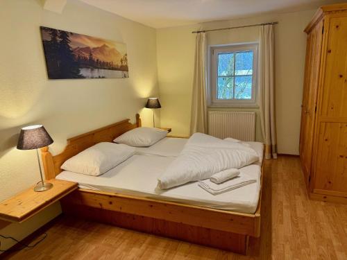 una camera da letto con letto in legno, lenzuola bianche e finestra di Familienfreundliche Ferienwohnung im schönen Thierseetal, FeWo 16 a Thiersee