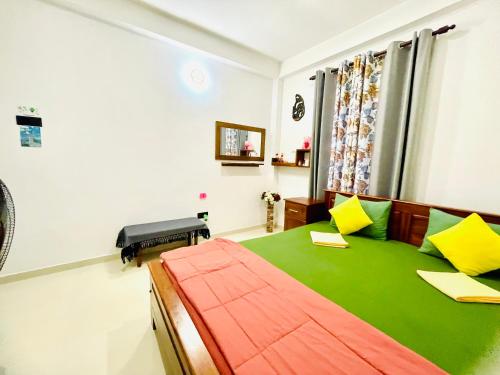 a bedroom with a bed with green sheets and yellow pillows at Ambuluwawa View Inn in Gampola