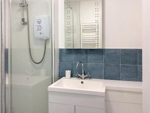 ein Bad mit einem Waschbecken, einem Spiegel und einer Dusche in der Unterkunft Langdale Cottage in Chapel Stile