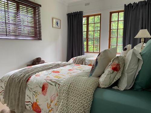 a bedroom with a bed with a comforter and pillows at Cape Chameleon in Nottingham Road