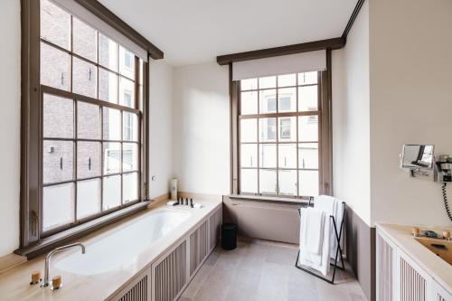 a bathroom with a bath tub and two windows at The Dylan Amsterdam - The Leading Hotels of the World in Amsterdam