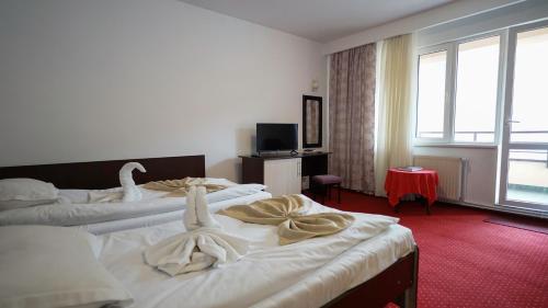 a hotel room with two beds with swans on them at Vila Trandafirul si Liliacul in Căciulata