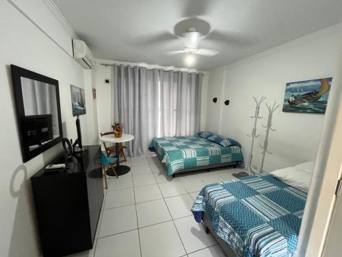 a bedroom with two beds and a television in it at STUDIO MANDARIM EM FRENTE A PRAIA DO GONZAGA in Santos