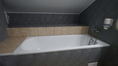 a bath tub in a bathroom with a tile wall at Vila Trandafirul si Liliacul in Căciulata