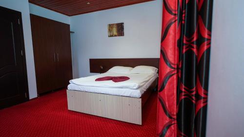 a bedroom with a bed with a red carpet at Vila Trandafirul si Liliacul in Căciulata