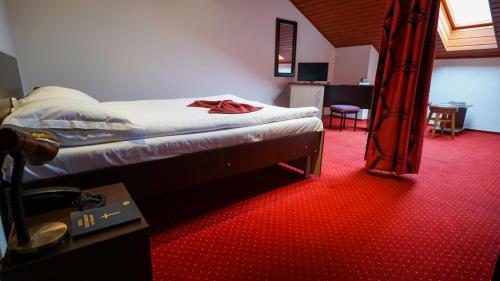 a bedroom with a bed and a red carpet at Vila Trandafirul si Liliacul in Căciulata