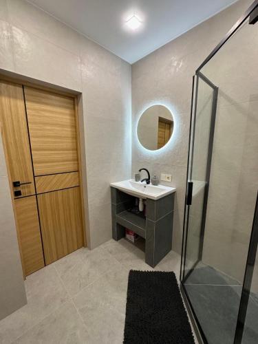 a bathroom with a sink and a mirror and a shower at Apartamenty Stepana Bandery 35 in Truskavets
