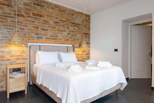 Un dormitorio con una cama con una pared de ladrillos. en White and black Suites Triple, en Sifnos