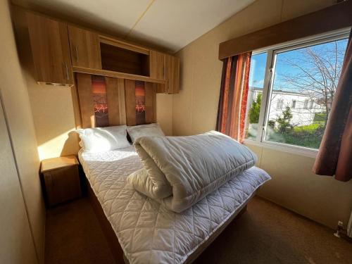 a small bedroom with a bed with a window at Lovely Caravan With Decking At Cherry Tree Holiday Park In Norfolk Ref 70528c in Great Yarmouth