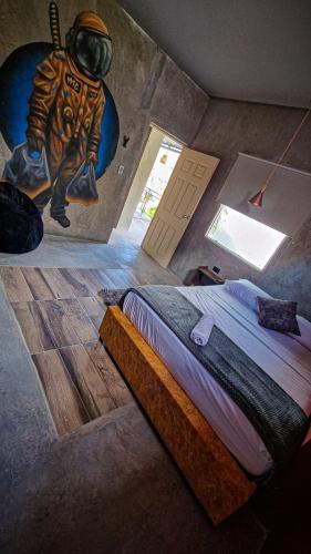 a room with a bed and a painting of a astronaut at Urban Hostal San Gil- Piscina Restaurante Bar in San Gil