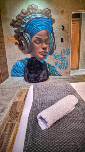 a painting of a woman with headphones on a wall with a towel at Urban Hostal San Gil- Piscina Restaurante Bar in San Gil