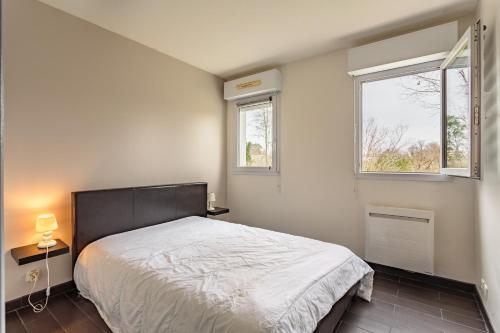 une chambre avec un lit et deux fenêtres dans l'établissement HARISTEGUY-Bien moderne avec confort 700m des commerces, à Saint-Jean-de-Luz