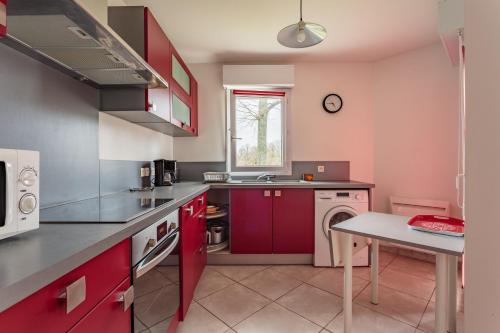 - une cuisine avec des placards rouges et un lave-linge dans l'établissement HARISTEGUY-Bien moderne avec confort 700m des commerces, à Saint-Jean-de-Luz