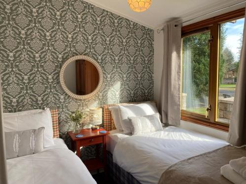 two beds in a hotel room with a mirror at Walled Garden Lodges Loch Lomond in Balloch