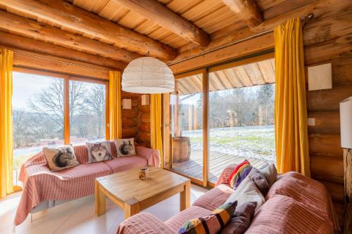 a living room with couches and a table andwindows at Chalet l'Epicurien - Au calme avec grand jardin in Saint-Martin-du-Puy