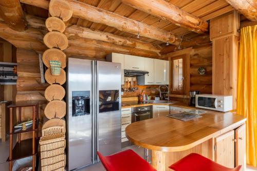 a kitchen with a refrigerator and a wooden ceiling at Chalet l'Epicurien - Au calme avec grand jardin in Saint-Martin-du-Puy