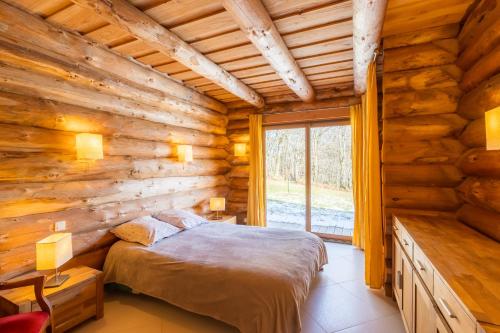 - une chambre dans une cabane en rondins avec un lit et une fenêtre dans l'établissement Chalet l'Epicurien - Au calme avec grand jardin, à Saint-Martin-du-Puy