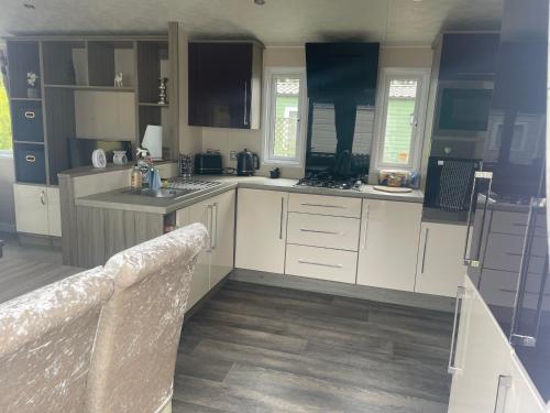 a large kitchen with white cabinets and a sink at Beautiful 2 bedroom caravan on Billing Aquadrome in Northampton