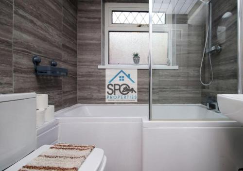 uma casa de banho com uma banheira, um WC e uma janela. em Modern 4BR Home-7 Guests-Business-Families-Netflix-Free Parking & WiFi em Pontnewynydd