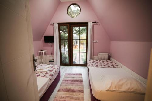 two beds in a room with pink walls and a window at İdavilla Bungalov & Bahçe in Akcay