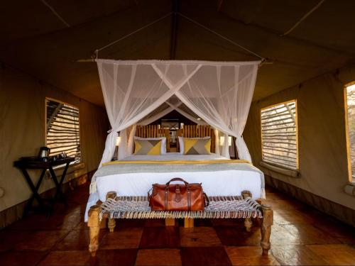 a bedroom with a large bed with a bag on a bench at Evolve Back Kalahari in Central Kalahari