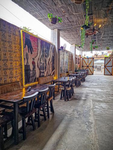 a row of tables and chairs in a room with paintings on the walls at Urban Hostal San Gil- Piscina Restaurante Bar in San Gil