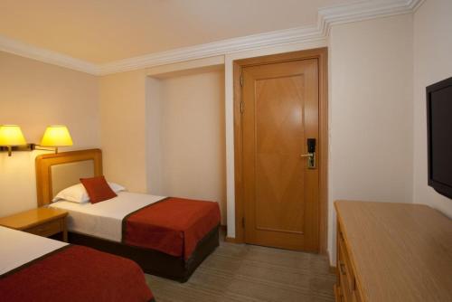 a hotel room with two beds and a door at Royal Beach eilat in Eilat