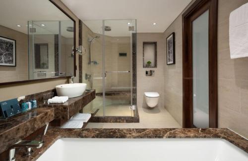 een badkamer met een bad, een wastafel en een douche bij Royal Beach eilat in Eilat