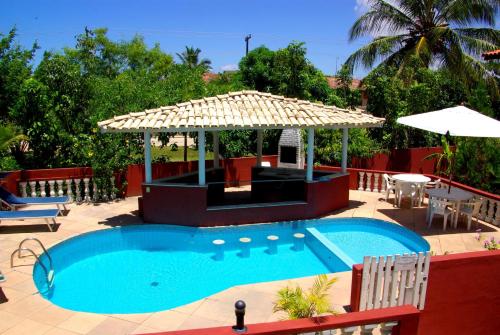 uma piscina com um guarda-sol, uma mesa e cadeiras em Porto Verano Residence em Porto Seguro