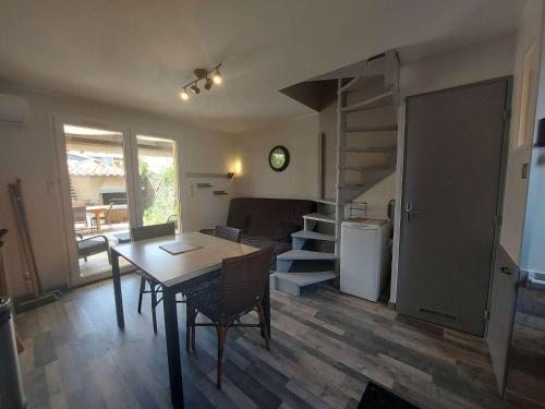 un salon avec une table et un escalier en colimaçon dans l'établissement Maison climatisée avec jardin, terrasse et piscine, proche des campings - Marseillan - FR-1-326-693, à Marseillan